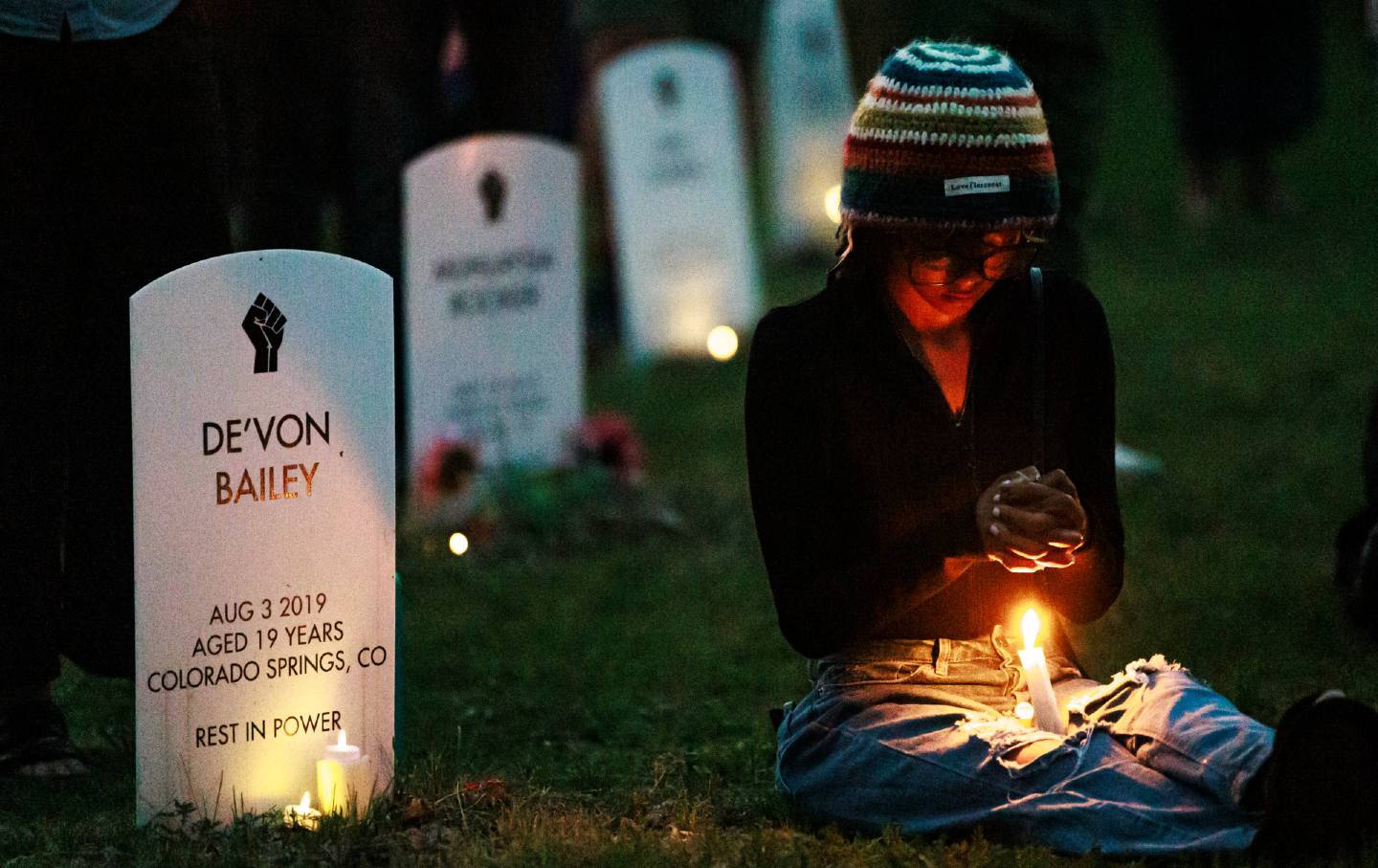 A community member holds a candle by the “Say Their Names” art installation cemetery with headstones representing Black people killed by police, during a vigil marking the fifth anniversary of George Floyd's death, at George Floyd Square in Minneapolis, Minnesota, on May 25, 2025.