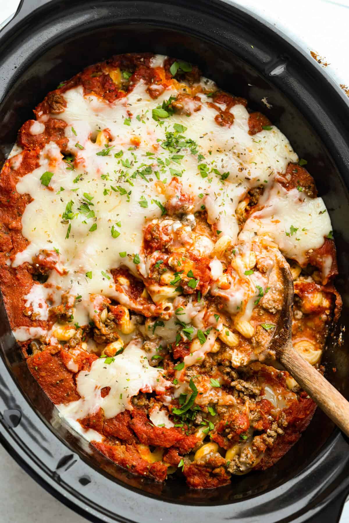 Crockpot million dollar pasta is rich, creamy, and straight-up dreamy. No boiling, no babysitting, just toss it all in and let your slow cooker work its magic! Overhead shot of crockpot million dollar pasta with a wooden spoon.