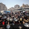 GAZA CITY, GAZA - JULY 23: Palestinians carrying pans, gather to receive hot meals, distributed by a charity organization in Gaza City, where residents are struggling to access food due to the ongoing Israeli blockade and attacks in Gaza City, Gaza on July 23, 2025.