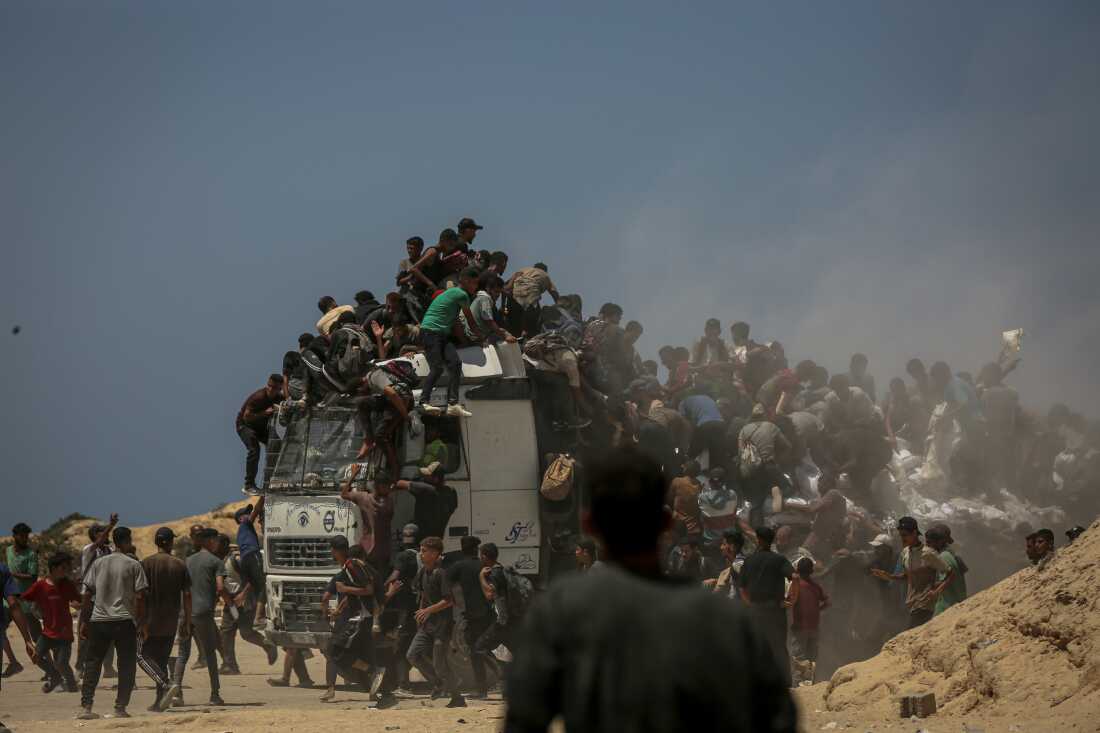 In this photo, Palestinian men and boys swarm on, around and on top of an aid distribution truck in Gaza City on July 27, 2025.