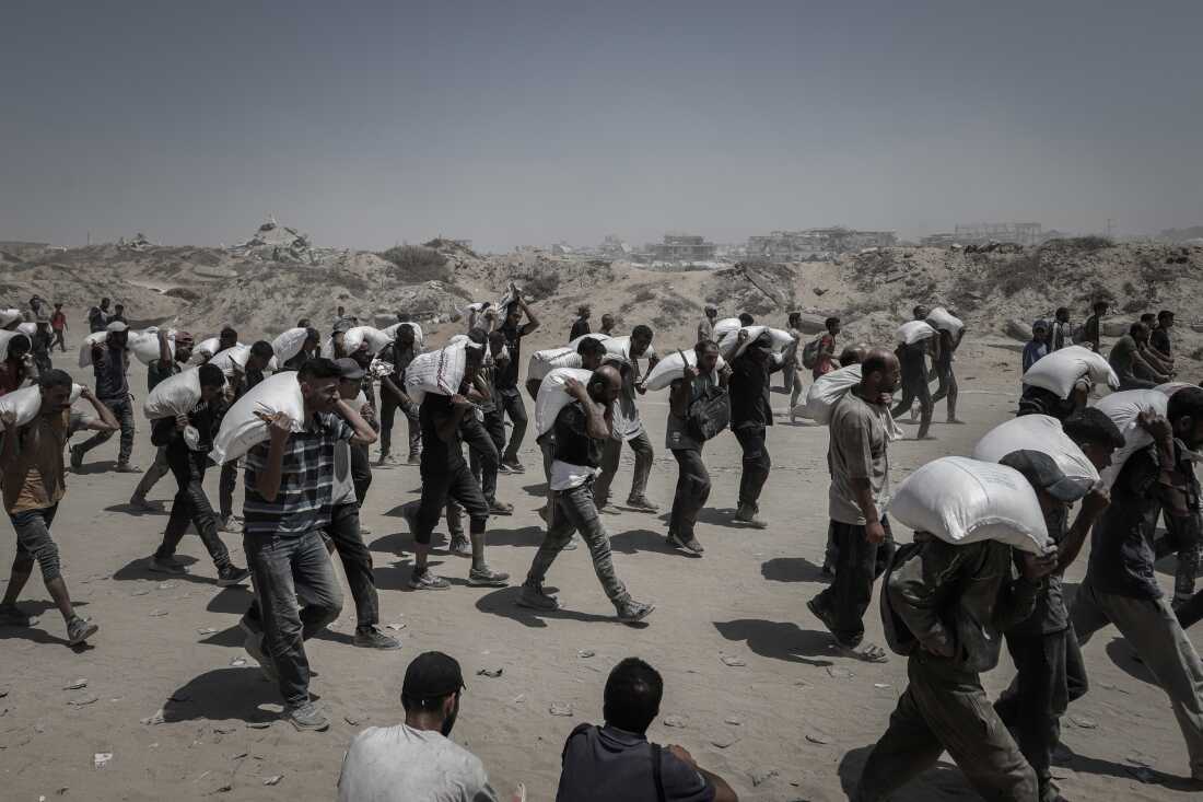Palestinians carry aid supplies which entered Gaza through Israel in Beit Lahia, northern Gaza, on Sunday, July 27, 2025. But NGO's have said not enough food is being allowed into Gaza. Israel says the U.N. is holding up deliveries