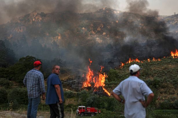 People watch the progress of a wildfire in Trancoso in Portugal on August 11, 2025.