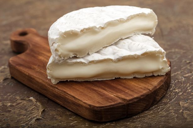 Soft cheese with white mold on a cutting board,