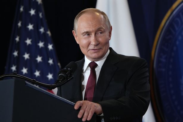 Russian President Vladimir Putin delivers a statement during a press conference with a US flag in the background
