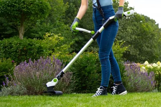 Woman trimming grass with a Gtech cordless grass trimmer.