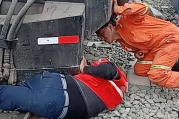 A 65-year-old train inspector was dragged under a train after leaping onto railway tracks to save a 14-year-old girl