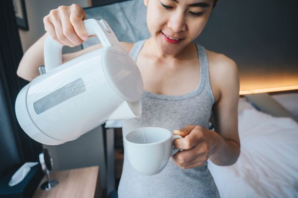 Woman pouring kettle water into a cup