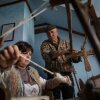 Lubov Hychka demonstrate how to weave the hunia fabric while Vasyl Hychka (unrelated), who takes care of the property where the loom is housed, helps with the rickety old machine.
