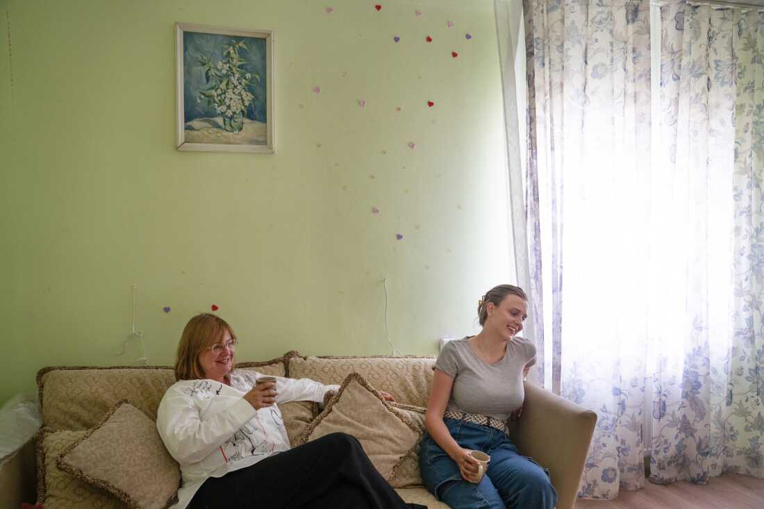 Iryna Schestova, 50, and her daughter, Liia Kazakova, 26, sit on a sofa in the living room of a friend's home in Horenychi, Ukraine.