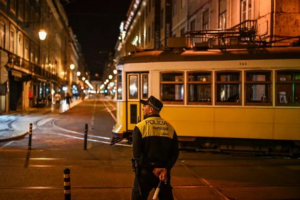 A policeman controls a tram being towed at downtown Lisbon