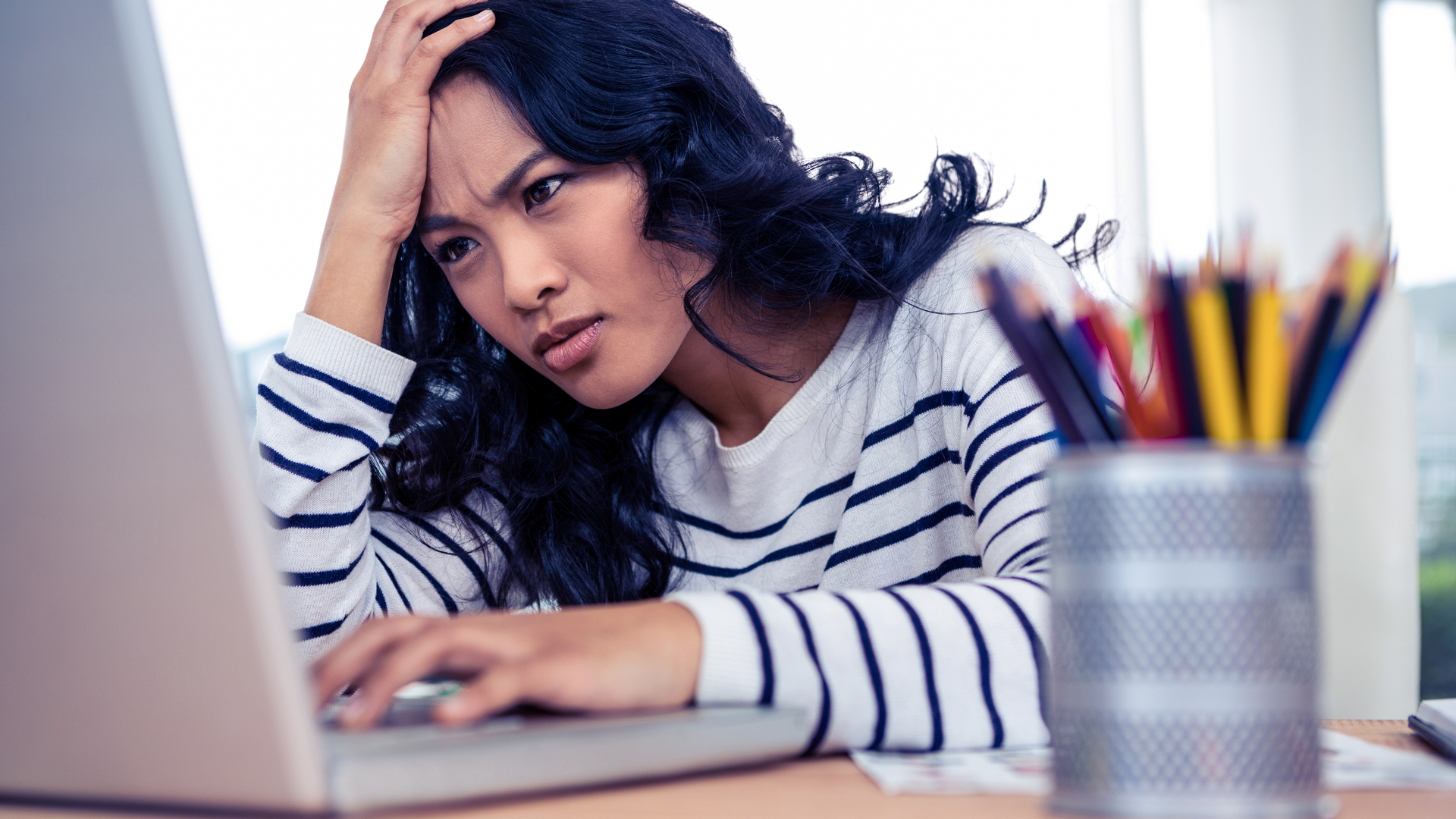 A woman looking puzzled at her Windows 11 laptop