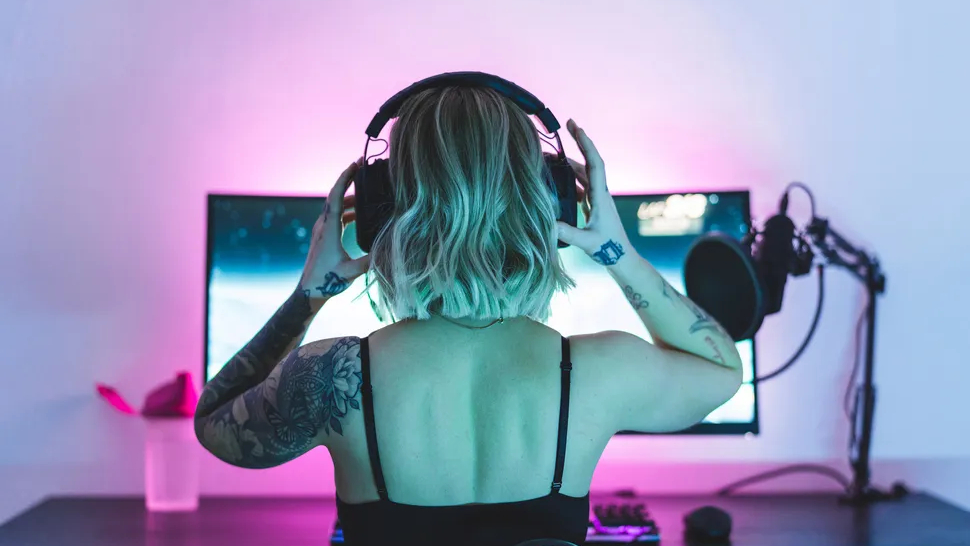 A gamer wearing headphones sat at a monitor on a desk
