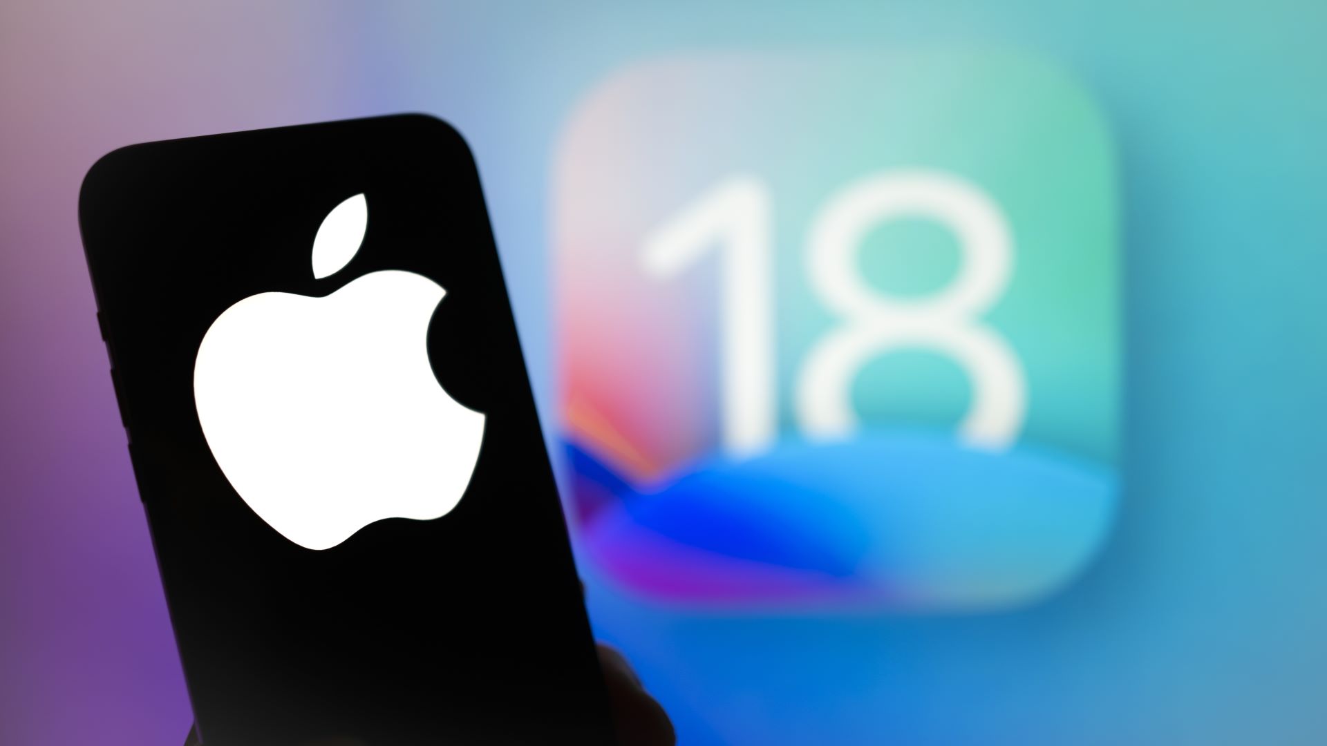 The Apple logo is seen with the iOS 18 operating system logo in the background on a mobile device