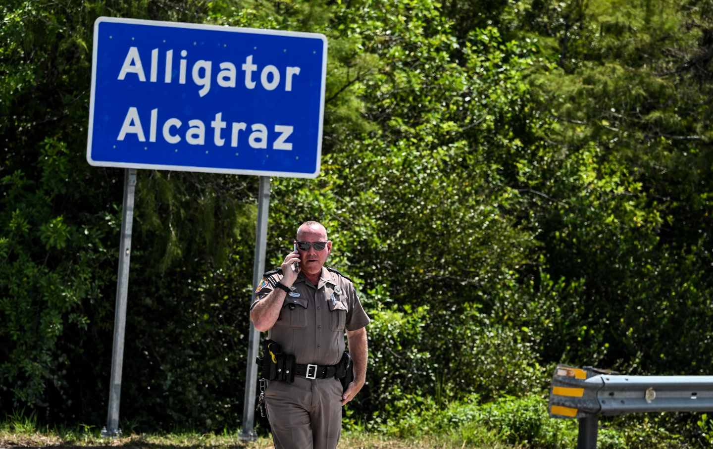A Florida Highway Patrol officer looks on as protesters gather to demand the closure of the immigrant detention center known as