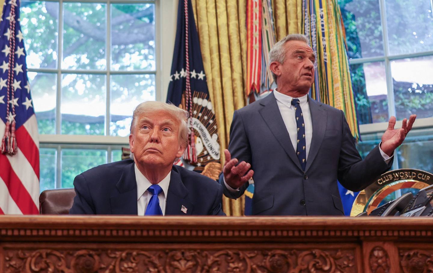 Robert Francis Kennedy Jr stands behind Donald Trump in the Oval Office
