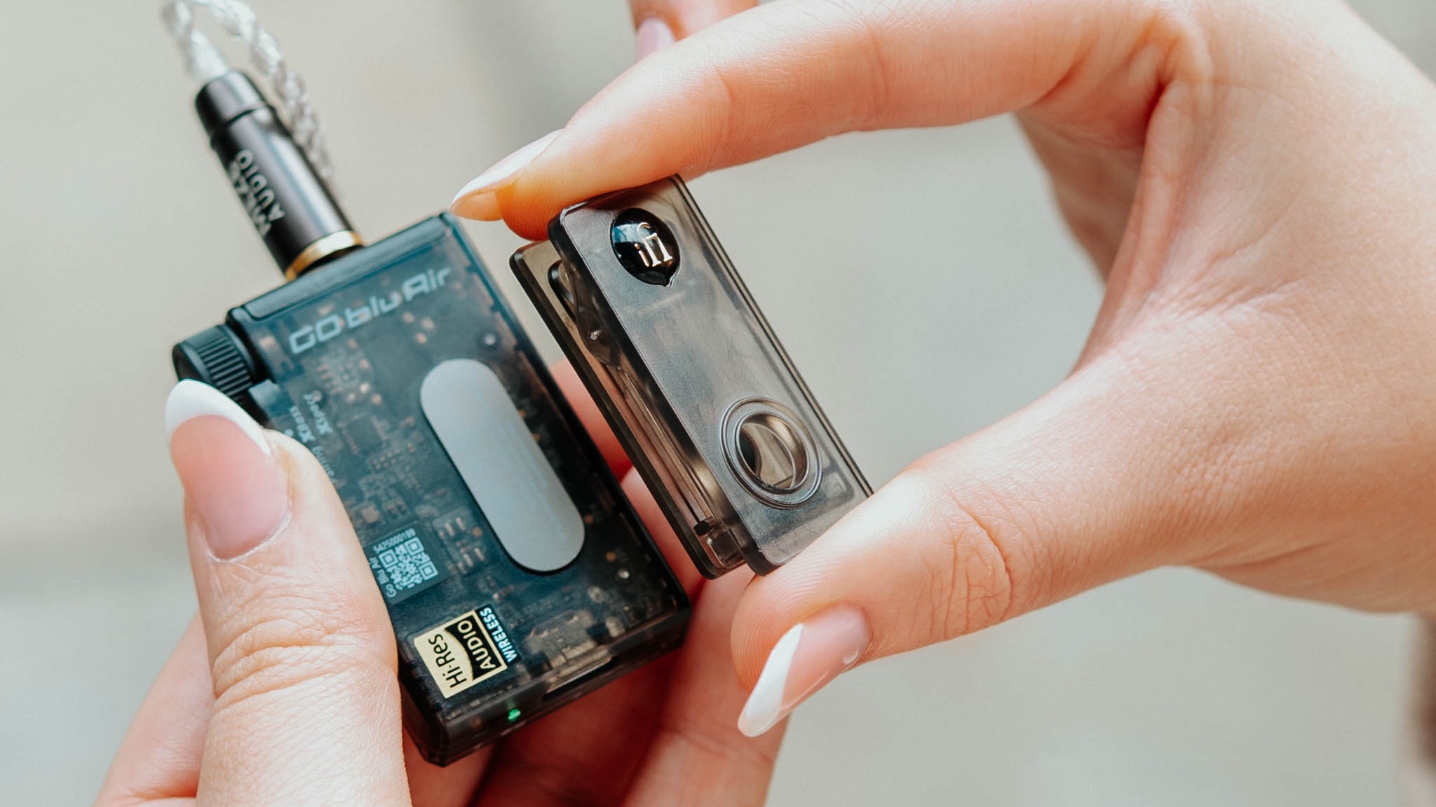 Lifestyle shots showing a model's hands holding the iFi GO Blu Air portable DAC