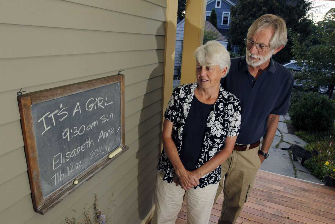 Eileen and Doug Flockhart look at a chalkboard announcing the birth of their seventh grandchild on the porch of their home in Exeter, N.H., Wednesday, Aug. 24, 2011.