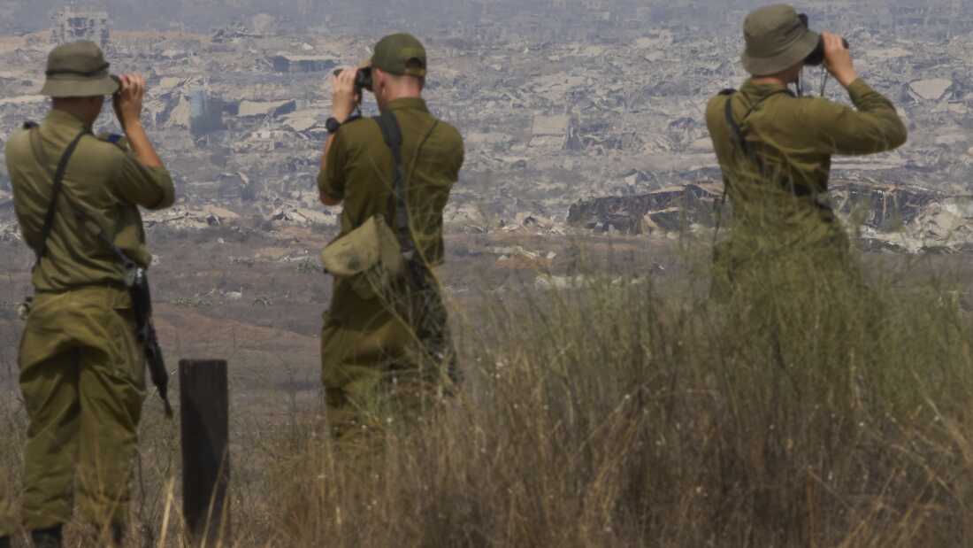 Israeli soldiers use binoculars to look at damaged buildings in the Gaza Strip from southern Israel on Wednesday, Aug. 13.