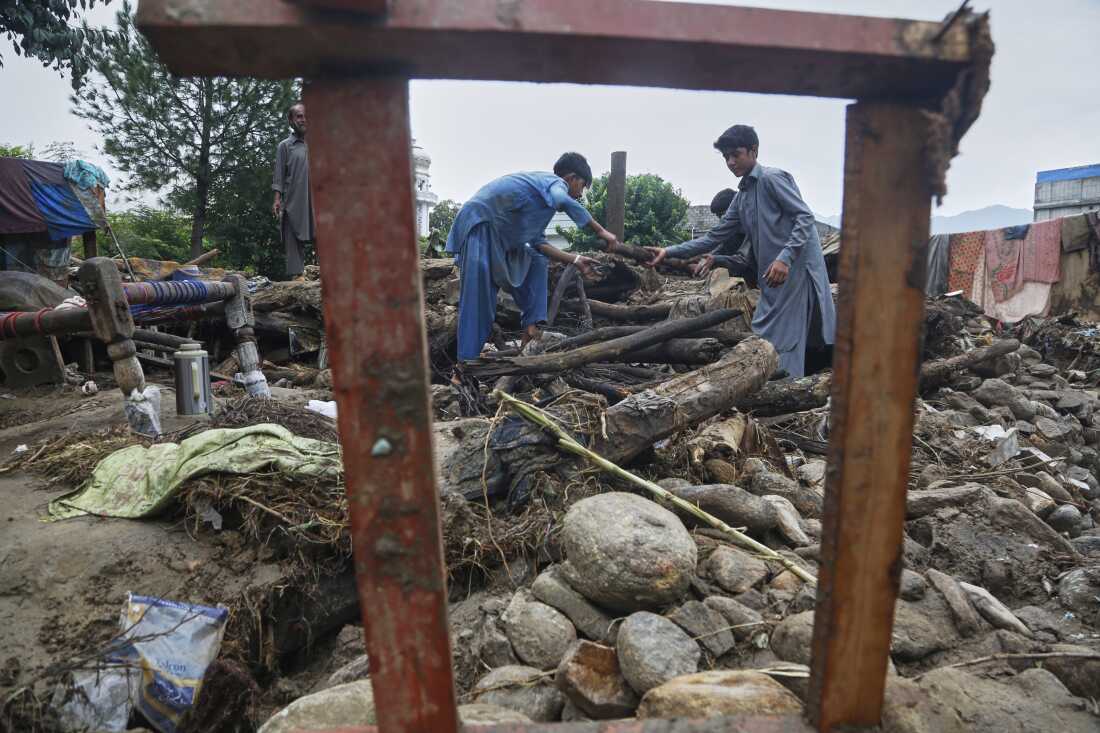 Boys collect wood and other useful items through the rubble of their damaged home following Friday