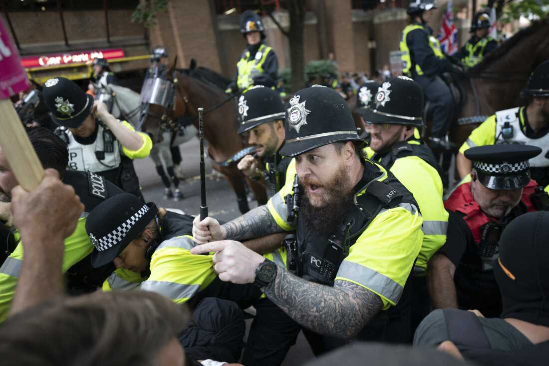 Mounted police officers scuffle with demonstrators during a protest by anti-migrant Abolish Asylum System and counter protesters at Castle Park in Bristol, England on Saturday.