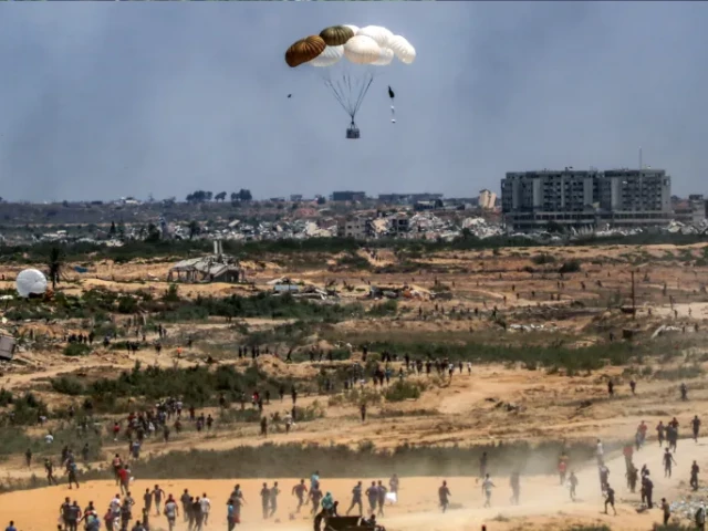 palestinians rush to the scene as air pallets carrying humanitarian aid parachute down after being dropped from a military plane over nuseirat in the central gaza strip on tuesday afp