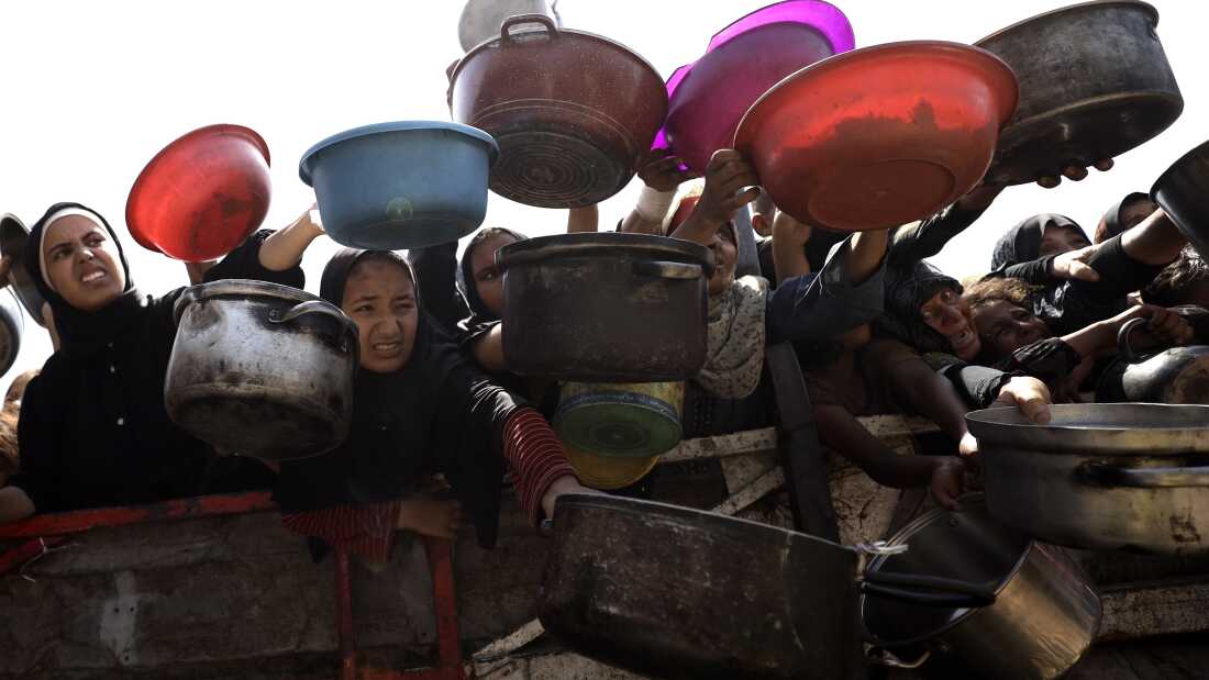 Palestinians, including children, receive hot meals, distributed by charity organizations, as people struggle to access food due to Israeli food blockade in Gaza City, Gaza on Aug.