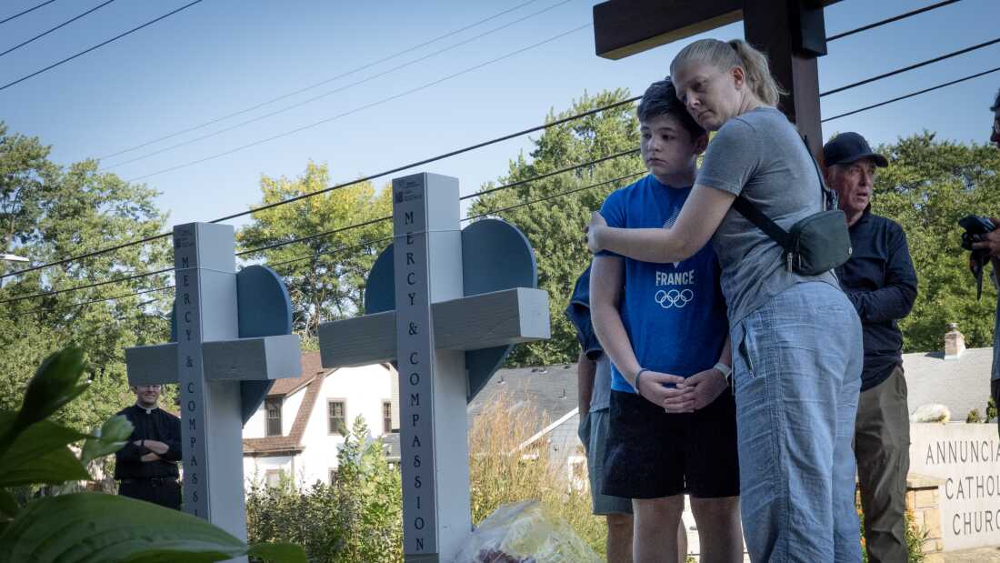 Community members visit a memorial for shooting victims in front of Annunciation Catholic Church in Minneapolis, one day after a shooter opened fire on students and parishioners during a Catholic school Mass.