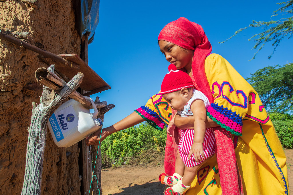 In the municipality of Manaure in La Guajira, Colombia, a woman washes her hands at an installation of hand-washing point known as tippy taps.