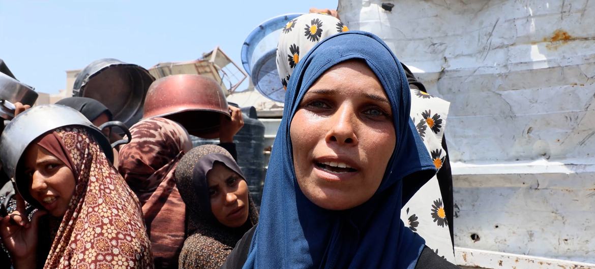 Um Muhammad, who fled from the Shujaiya neighbourhood in eastern Gaza City to its western areas, waits to get food. Um Muhammad, who fled from the Shujaiya neighbourhood in eastern Gaza City to its western areas, waits to get food.