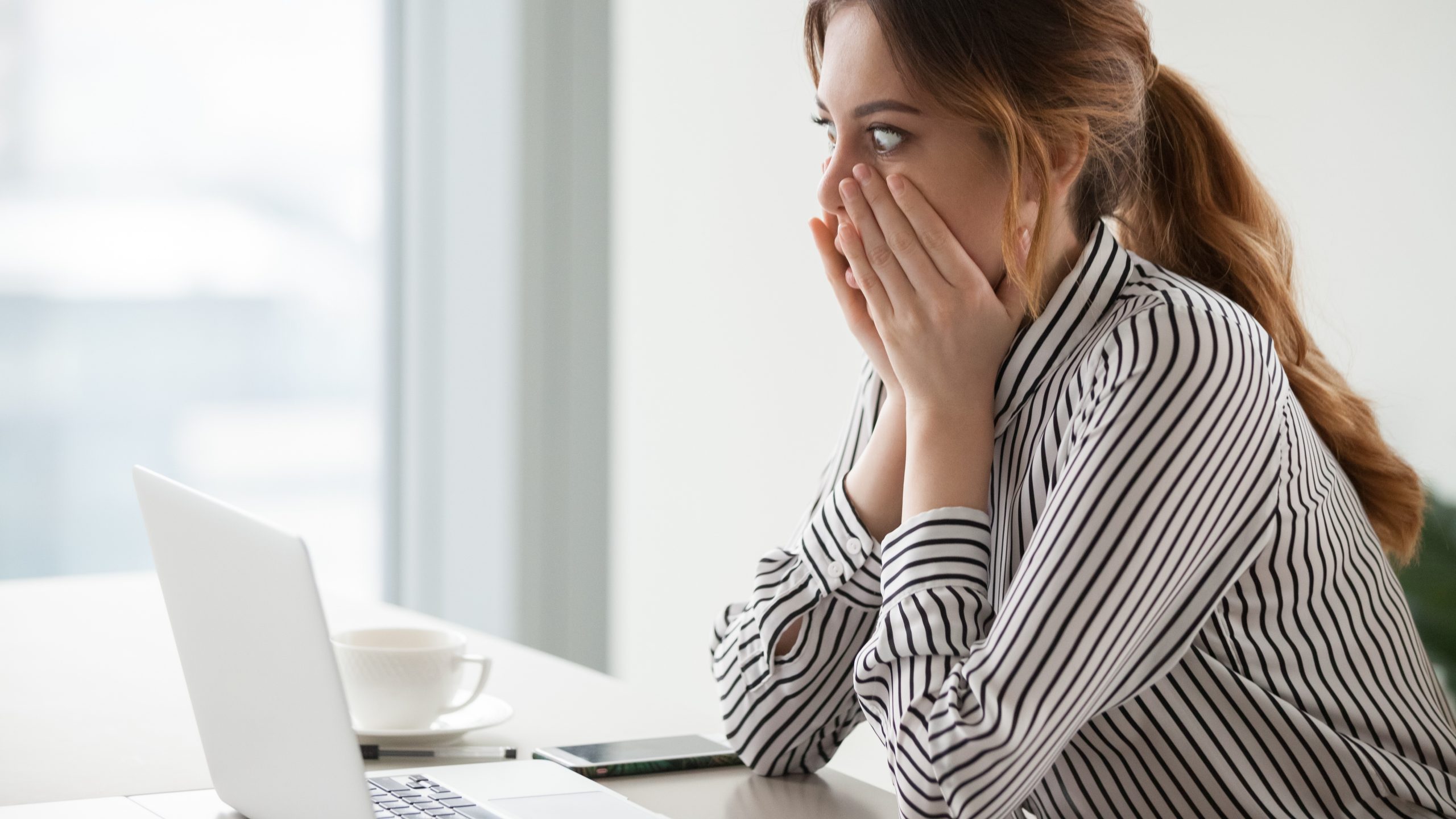 Shocked woman worker looking at laptop that has failed to boot