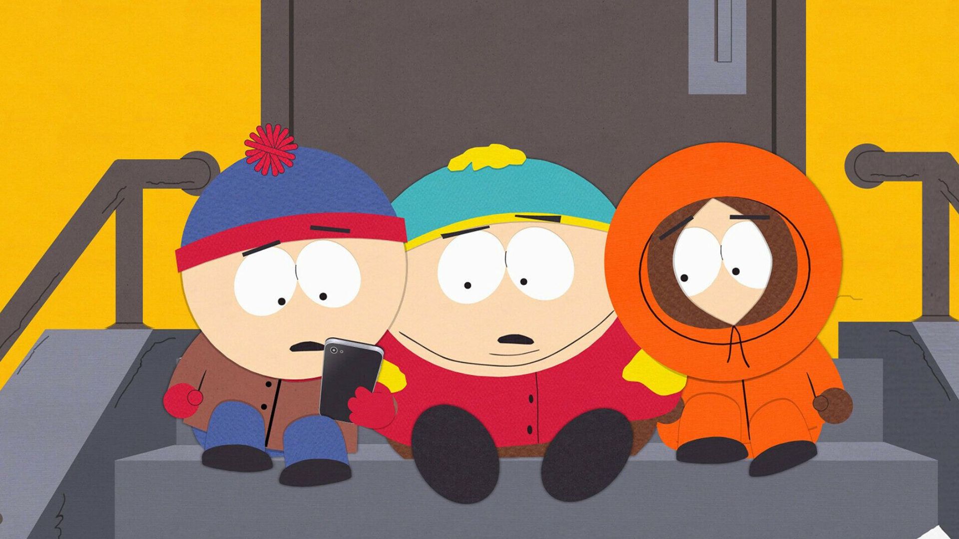Kenny, Stan and Eric look at something on Stan's phone while sitting on a staircase