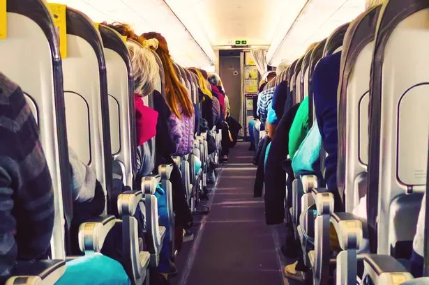 Picture during flight in a commercial airplane full with people sitting in seats taken picture from the end of the aisle with nice vanishing point.