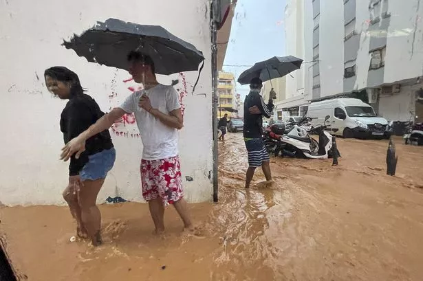 People walk along flooded streets in Ibiza, Spain, 30 September 2025, after heavy rains that have caused several floods throughout the island.