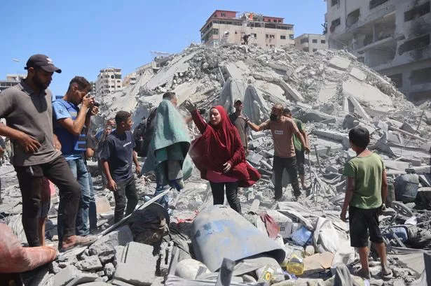 Palestinians look for salvageable items amid the rubble of the Tiba tower which crashed to the ground moments after Israeli strikes targeted the high-rise building in Gaza City on September 10