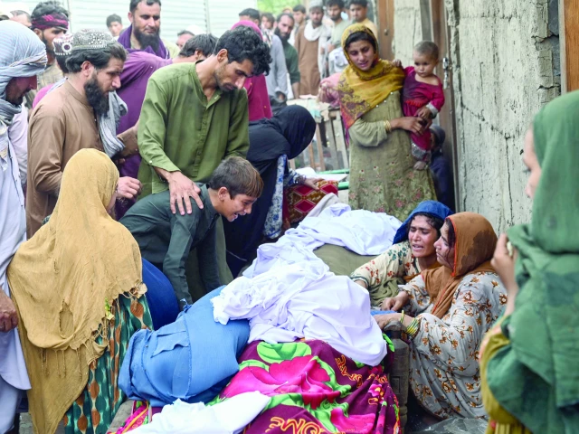 relatives of victims mourn outside a damaged house following earthquakes in the mazar dara village of nurgal a district of the kunar province photo afp