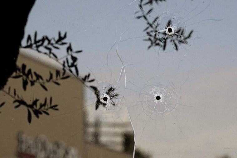 Three shots are visible in a window at the ABC10 offices