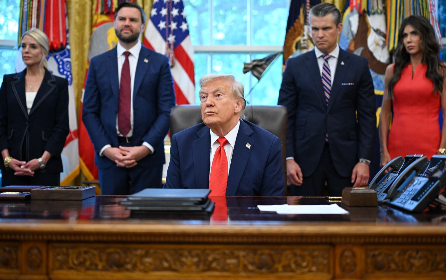 Trump stands in the oval office in front of US Attorney General Pam Bondi, Vice President JD Vance, Defense Secretary Pete Hegseth and Secretary of Homeland Security Kristi Noem.