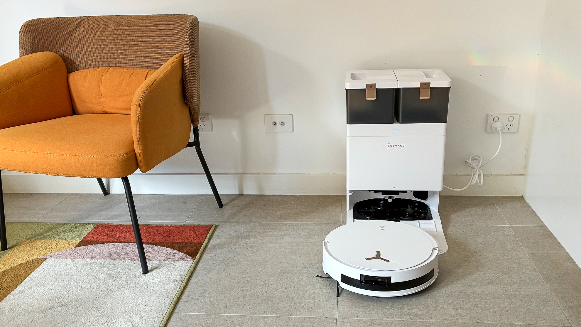 Ecovacs Deebot T50 Max Pro Omni beside a yellow chair and carpet