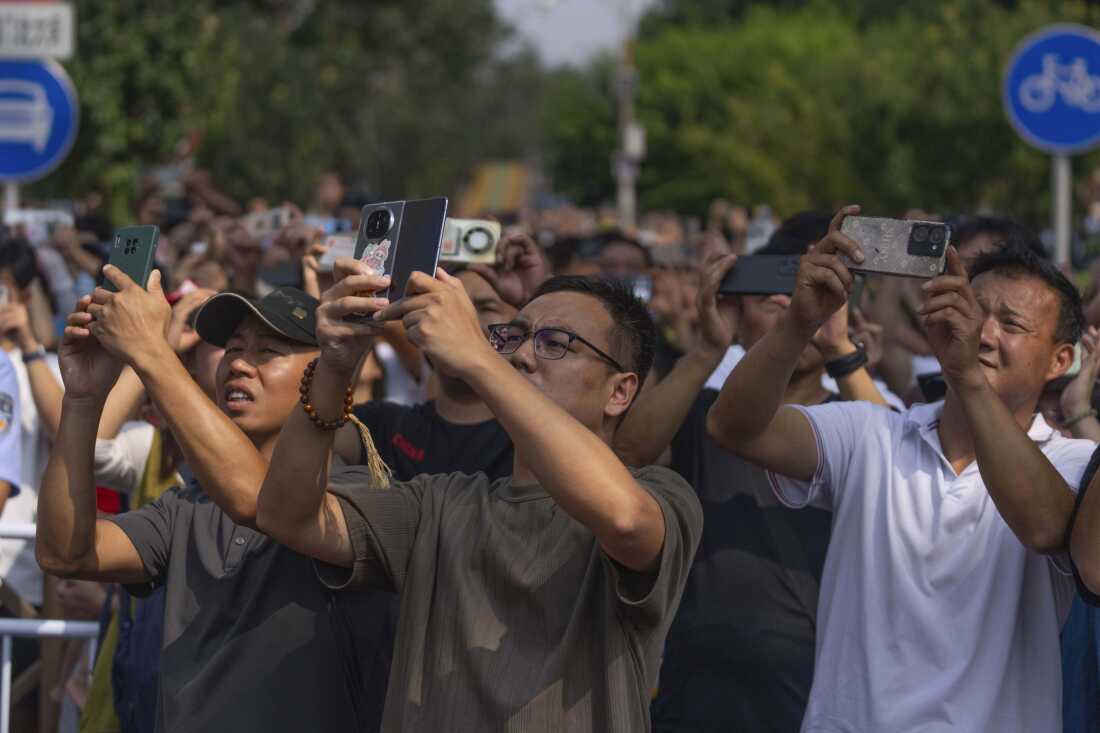 People use smartphones to film planes fly in formation during a military parade to commemorate the 80th anniversary of the end of World War II in Beijing on Wednesday.