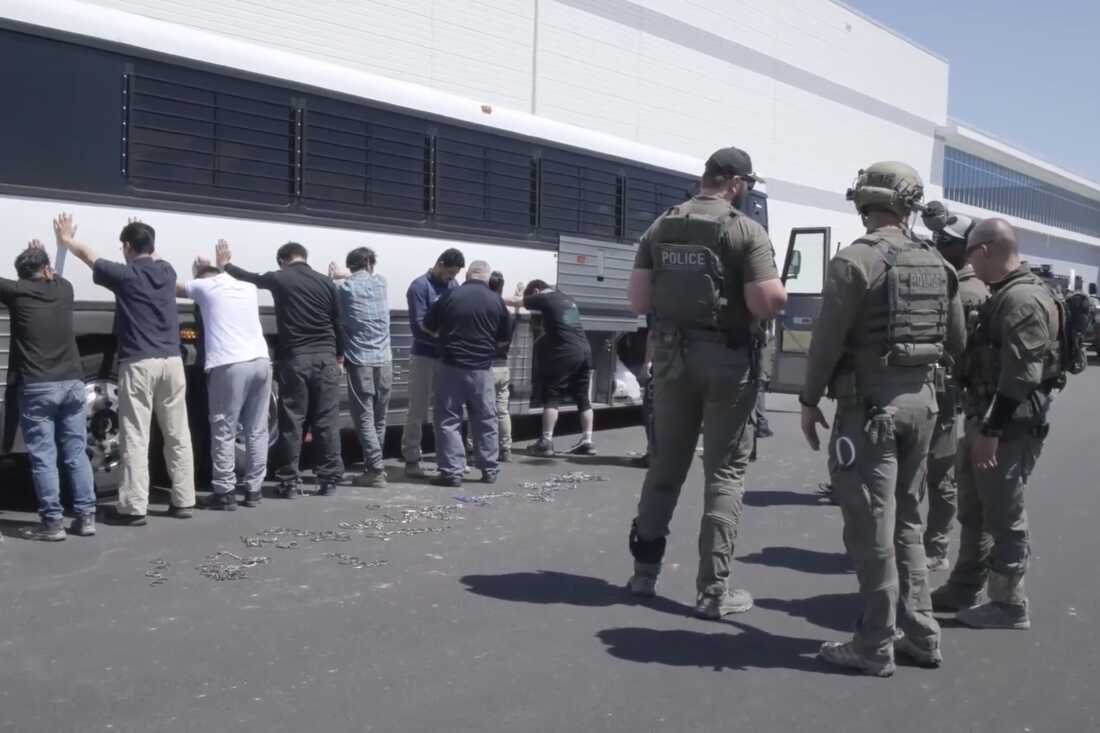This image from video provided by U.S. Immigration and Customs Enforcement via DVIDS shows manufacturing plant employees waiting to have their legs shackled at the Hyundai Motor Group’s electric vehicle plant, Thursday, Sept. 4, 2025, in Ellabell, Ga.