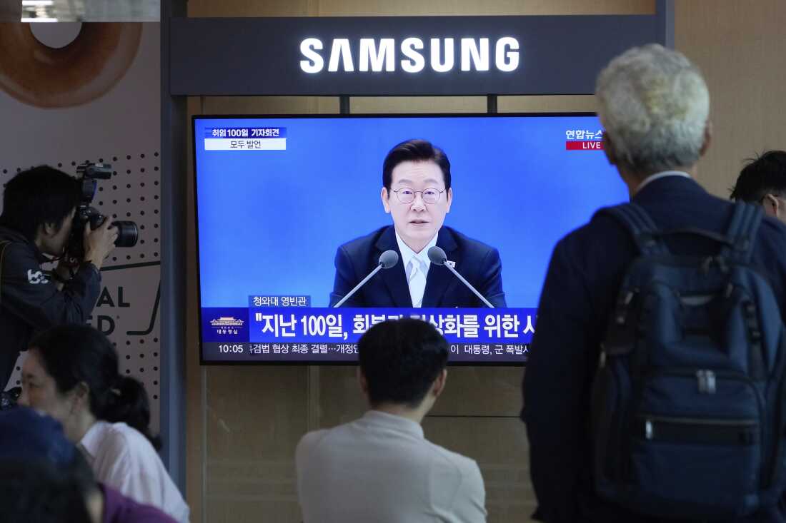 People watch a TV screen showing the live broadcast of South Korean President Lee Jae Myung