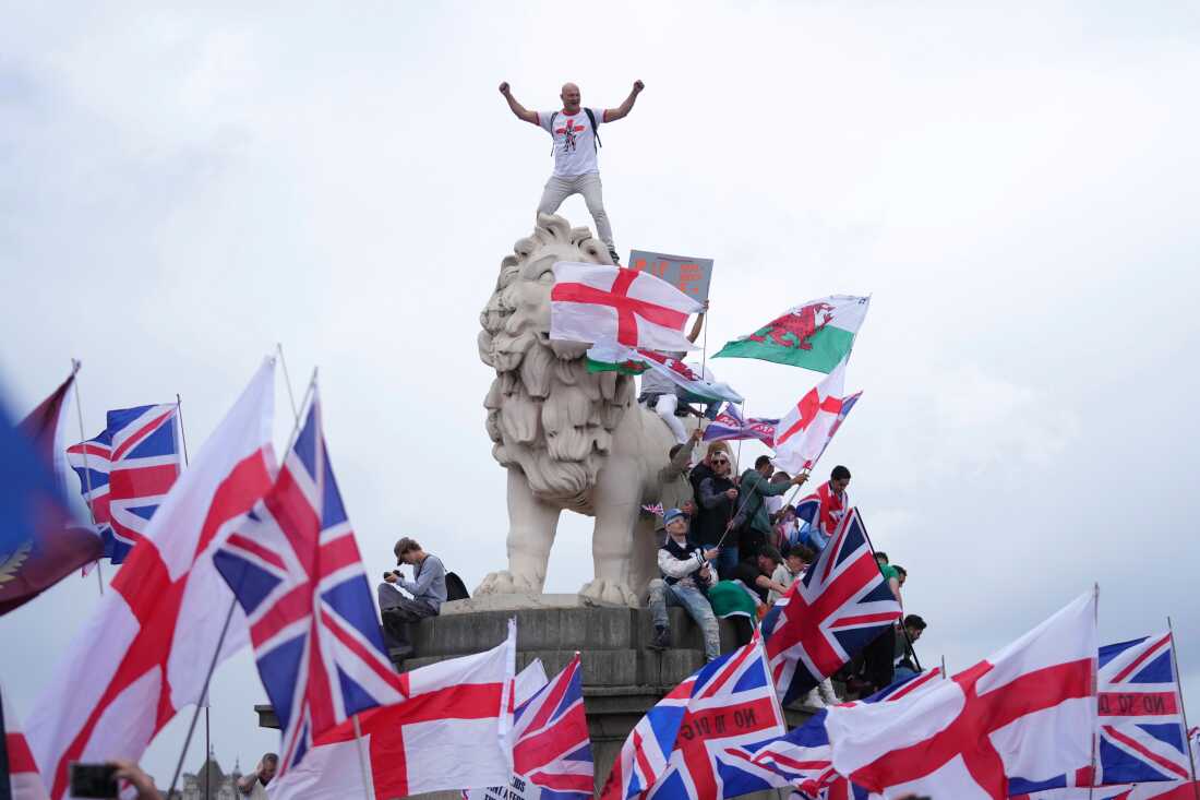A demonstrator stands on the head of the South Bank lion that sits on the side of the Westminster Bridge, during a Tommy Robinson-led Unite the Kingdom march and rally in London, on Saturday.