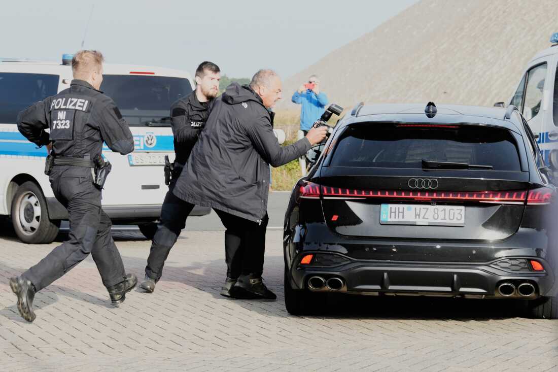 Police officers try to stop a British photographer as he takes pictures inside a car leaving a prison, carrying a suspect in the 2007 disappearance of British toddler Madeleine McCann, in Sehnde, Germany, Wednesday, Sept. 17, 2025.