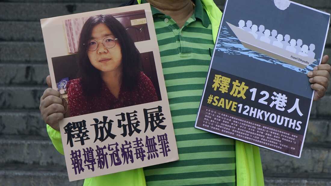 A pro-democracy activist holds placards with the picture of Chinese citizen journalist Zhang Zhan outside the Chinese central government