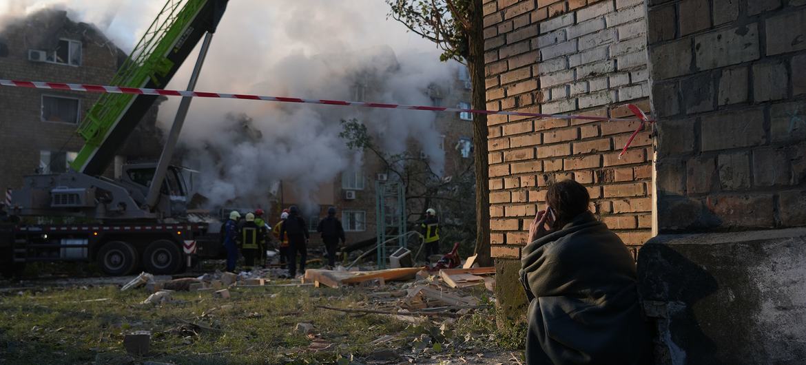 A resident near the ruins of a residential building in Kyiv, watching as emergency crews search for survivors following a missile strike in the early hours of the morning on 28 August.