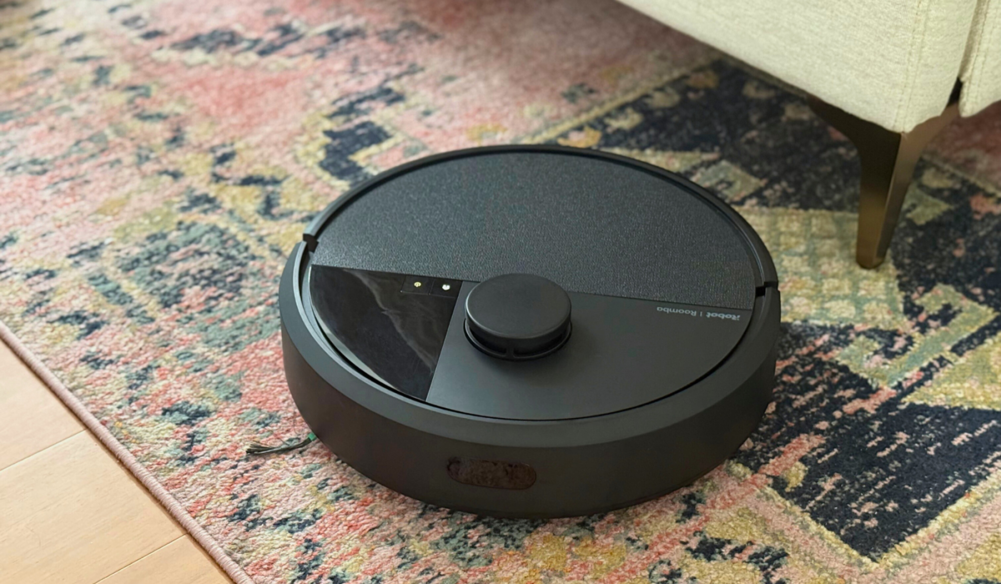Roomba Plus 405 Combo robot vacuum cleaning rug near bed frame