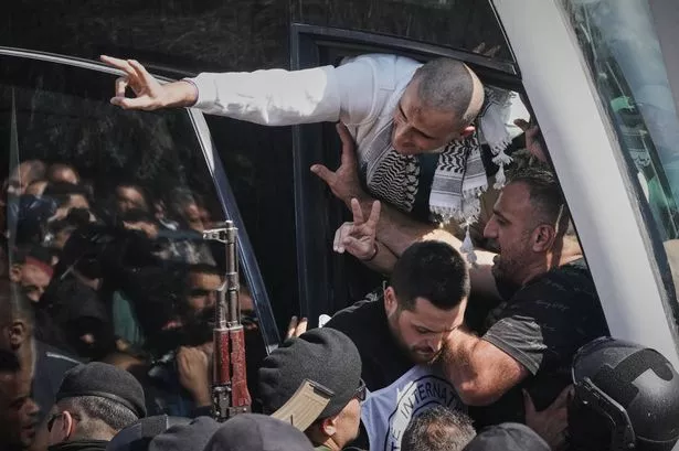 Palestinian prisoners wave to the crowd after being released from Israeli prison following a ceasefire agreement between Israel and Hamas, in the West Bank city of Ramallah, Monday, Oct. 13, 2025. (AP Photo/Mahmoud Illean)