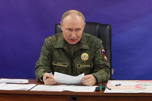 Vladimir Putin wearing uniform as he reads a statement