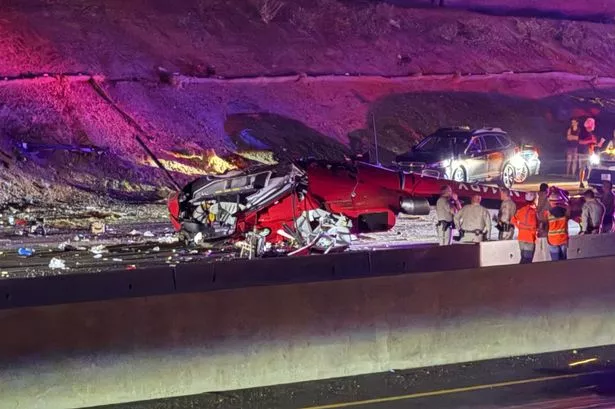 Law enforcement officers stand near the wreckage of a helicopter that crashed on eastbound Highway 50 in Sacramento, Calif., Monday, Oct. 6, 2025. (Robert Petersen via AP)