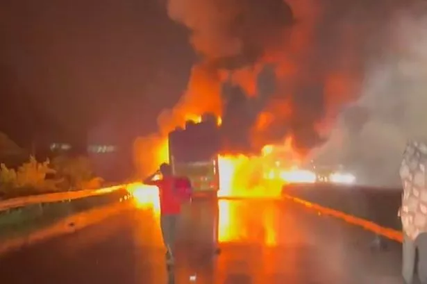 The passengers bus on fire as a man looks at the blaze